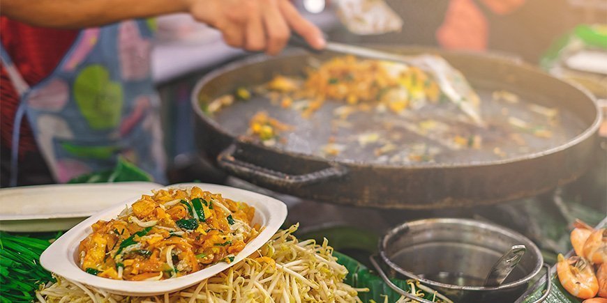 Frau macht Pad Thai auf einem Markt in Bangkok