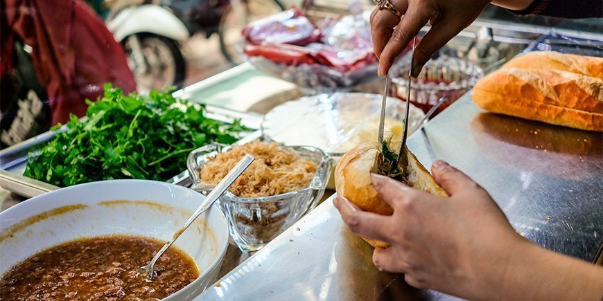 Frau bei der Zubereitung eines Banh Mi-Sandwichs in Ho-Chi-Minh-Stadt, Vietnam
