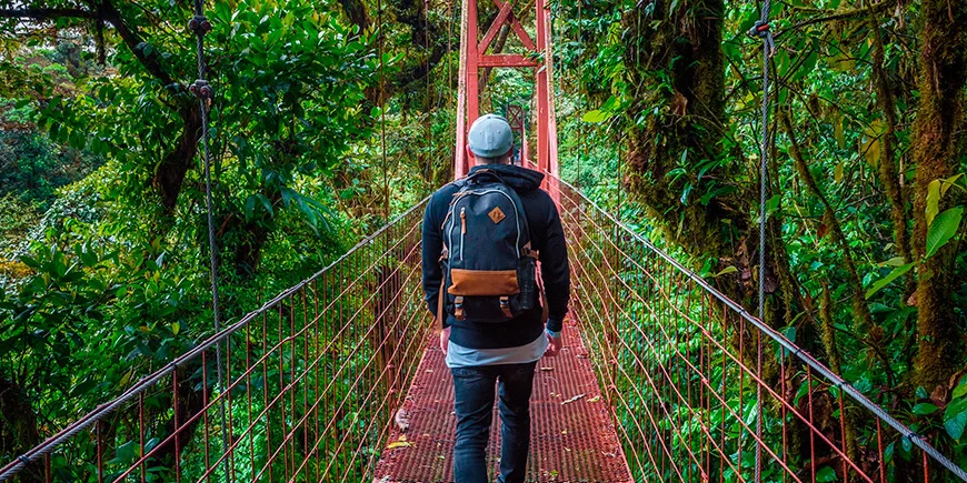 Mann geht allein auf einer Hängebrücke im Nebelwald von Monteverde in Costa Rica